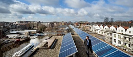 Pieter Oppermann tussen de zonnepanelen van HuurDeZon op huurwoningen van Woningcorporatie Eigen Haard.